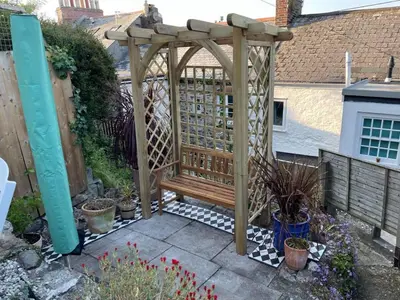 a wooden pergola with a bench in a garden at Smugglers Cottage in Penryn Nr Falmouth in Penryn