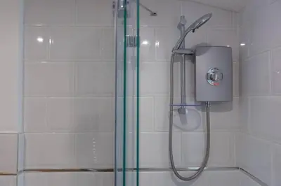 a shower with a glass door in a bathroom at Homely Cottage with Sun Terrace Short Walk to Beach in Porthleven