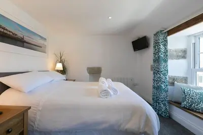 a bedroom with a white bed with towels on it at Homely Cottage with Sun Terrace Short Walk to Beach in Porthleven