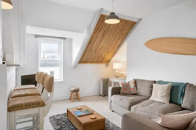 a living room with a couch and a table at Beach-Style Flat 2 Min Walk to Tolcarne Beach in Newquay