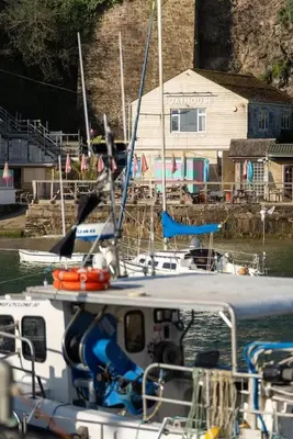 a boat is docked in the water near a house at Beach-Style Flat 2 Min Walk to Tolcarne Beach in Newquay
