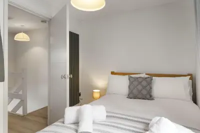 a bedroom with a bed with white sheets at Modern Townhouse in Central Falmouth Nr Seafront in Falmouth