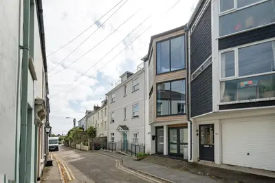 an empty street with white buildings and a car at Modern Townhouse in Central Falmouth Nr Seafront in Falmouth