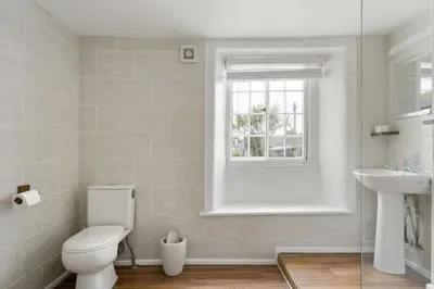a white bathroom with a toilet and a sink at 18th Century Cottage with Garden Central Newquay in Newquay