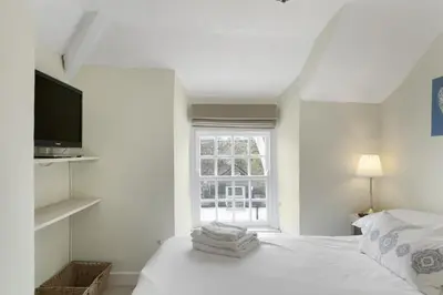 a white bedroom with a bed and a window at 18th Century Cottage with Garden Central Newquay in Newquay