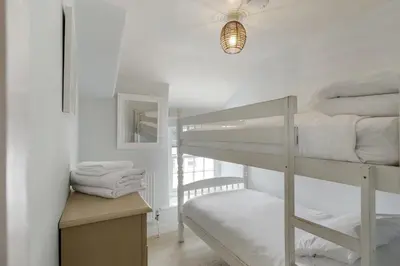 a bedroom with a bunk bed and a desk with towels at 18th Century Cottage with Garden Central Newquay in Newquay