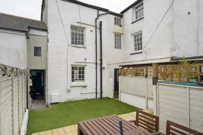 an empty backyard with a lawn in front of a house at 18th Century Cottage with Garden Central Newquay in Newquay