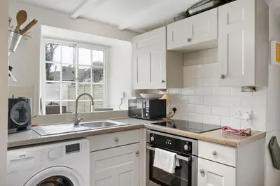 a white kitchen with a sink and a microwave at 18th Century Cottage with Garden Central Newquay in Newquay