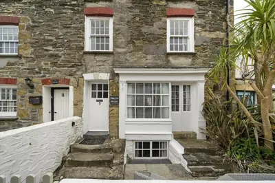 an old stone house with white doors and a white fence at 18th Century Cottage with Garden Central Newquay in Newquay