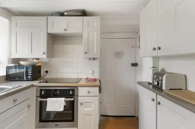 a kitchen with white cabinets and a stove top oven at 18th Century Cottage with Garden Central Newquay in Newquay