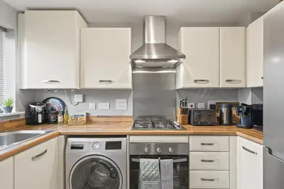 a kitchen with a stove and a washing machine at Stylish Home with Private Parking & Garden in Newquay