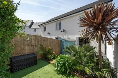 a backyard with a fence and a palm tree at Stylish Home with Private Parking & Garden in Newquay