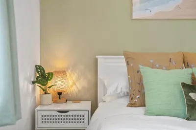 a bedroom with a bed with green pillows and a lamp at Stylish Home with Private Parking & Garden in Newquay