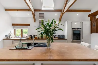 a kitchen with a wooden table with a vase of flowers at Swift Barn Lambest Farm Menheniot Cornwall in Menheniot
