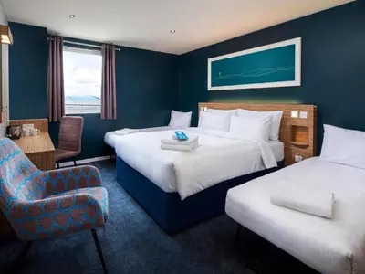 a hotel room with two beds and a chair at Travelodge Wadebridge in Wadebridge