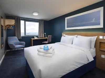 a bedroom with a large bed with towels on it at Travelodge Wadebridge in Wadebridge