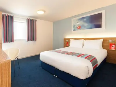 a hotel room with a large bed and a table at Travelodge Wadebridge in Wadebridge