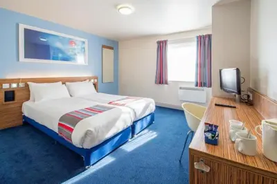 a hotel room with a bed and a desk and a television at Travelodge Bodmin Roche in Roche