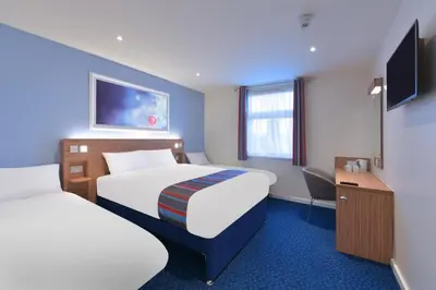 a hotel room with two beds and a desk at Travelodge Bodmin Roche in Roche
