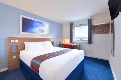 a hotel room with a large bed and a window at Travelodge Bodmin Roche in Roche