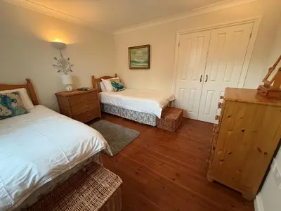 a bedroom with two beds and a wooden floor at Caldarvan in Wadebridge