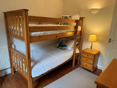two bunk beds in a room with a lamp and a table at Caldarvan in Wadebridge