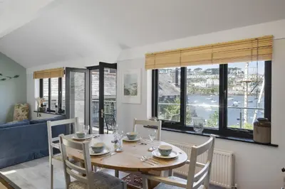 a dining room with a table and chairs and windows at Beautiful Cottage on the Water Front Polruan in Polruan