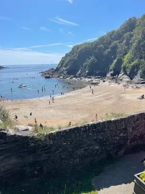 a beach with a bunch of people in the water at Beautiful Cottage on the Water Front Polruan in Polruan