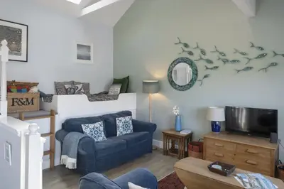 a living room with a blue couch and a tv at Beautiful Cottage on the Water Front Polruan in Polruan