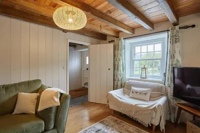a living room with a couch and a tv and a window at The Old Post Office Private Parking & Garden in Newquay