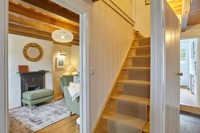 a staircase in a home with a green chair and a fireplace at The Old Post Office Private Parking & Garden in Newquay