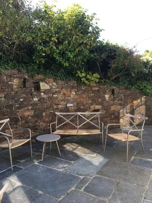 a group of chairs and a table and a brick wall at The Old Post Office Private Parking & Garden in Newquay