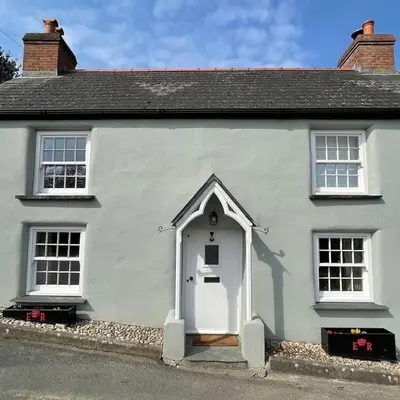 a white house with a white door and two windows at The Old Post Office Private Parking & Garden in Newquay