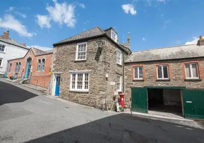 an old brick building with a green door on a street at Sundance Cottage Central Fowey with Sea Views in Fowey
