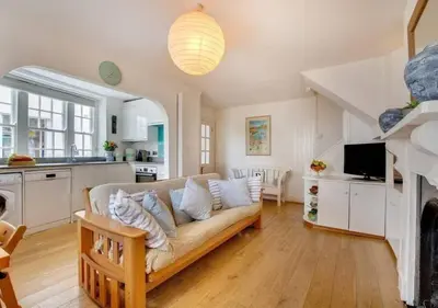 a living room with a couch and a kitchen at Sundance Cottage Central Fowey with Sea Views in Fowey