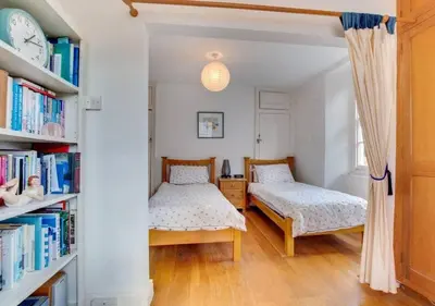 a bedroom with two beds and a book shelf at Sundance Cottage Central Fowey with Sea Views in Fowey