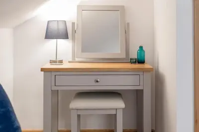 a dressing table with a mirror and a lamp and a stool at Spacious Flat A Few Mins Walk to Carlyon Bay Beach in Carlyon Bay