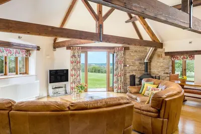 a living room with brown leather furniture and windows at 4 Bed in Wadebridge oc-t34227 in Saint Issey
