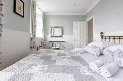 a bedroom with a large white bed with pillows at 2 Bedroom Cottage Close to Perranporth Beach in Roche