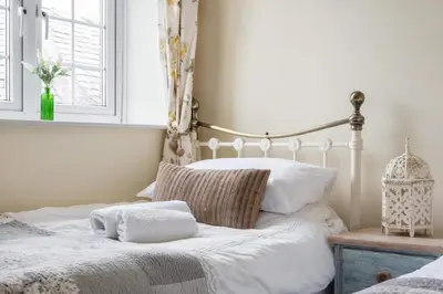 a bedroom with a bed with white sheets and a window at 2 Bedroom Cottage Close to Perranporth Beach in Roche