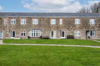 a large brick building with benches in the yard at 2 Bedroom Cottage Close to Perranporth Beach in Roche