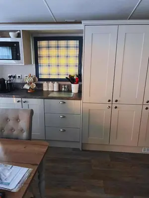 a kitchen with white cabinets and a wooden table at St Minver Hideaway in Saint Minver