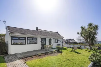 a white house with a patio and a yard at Beach House & Garden in St Merryn Private Parking in St Merryn