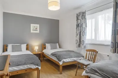 a bedroom with two beds and a chair and a window at Beach House & Garden in St Merryn Private Parking in St Merryn
