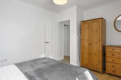 a bedroom with a bed and a wooden cabinet at Beach House & Garden in St Merryn Private Parking in St Merryn