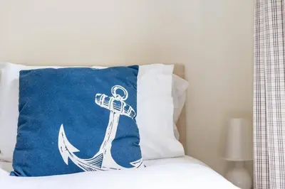 a pillow with an anchor on it sitting on a bed at Gin O'Clock Mevagissey Level Walk to Harbour in Mevagissey