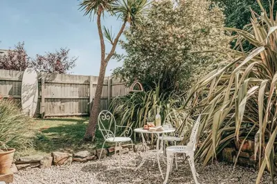 a table and chairs in a backyard with a fence at Romantic Converted Barn Perfect St Agnes Location in St. Agnes