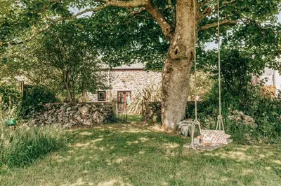 a swing under a tree in a yard at Romantic Converted Barn Perfect St Agnes Location in St. Agnes