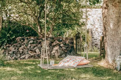 a swing in a yard with two pillows on it at Romantic Converted Barn Perfect St Agnes Location in St. Agnes