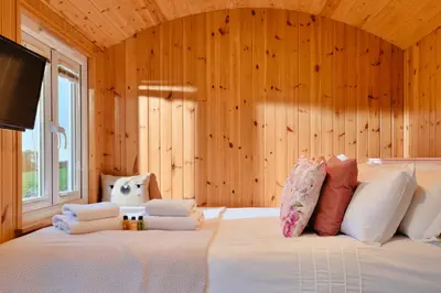 a bedroom with a large white bed with wooden walls at Finest Retreats - Demelza Shepherds Hut in Grade